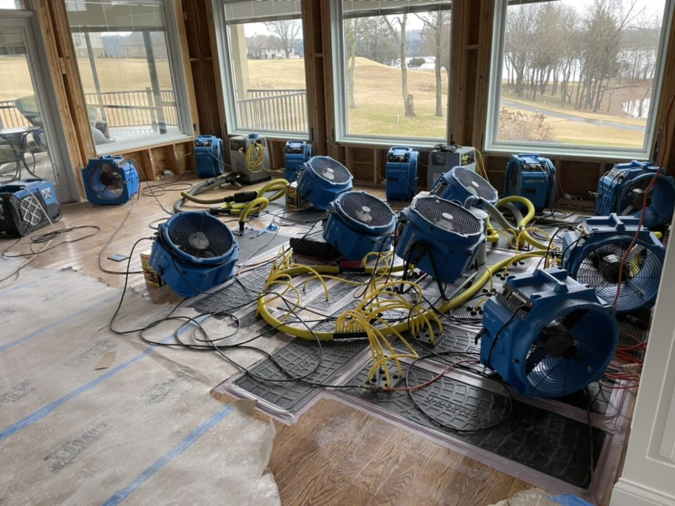 Industrial air movers and dehumidifiers deployed in a home for structural drying after flood damage