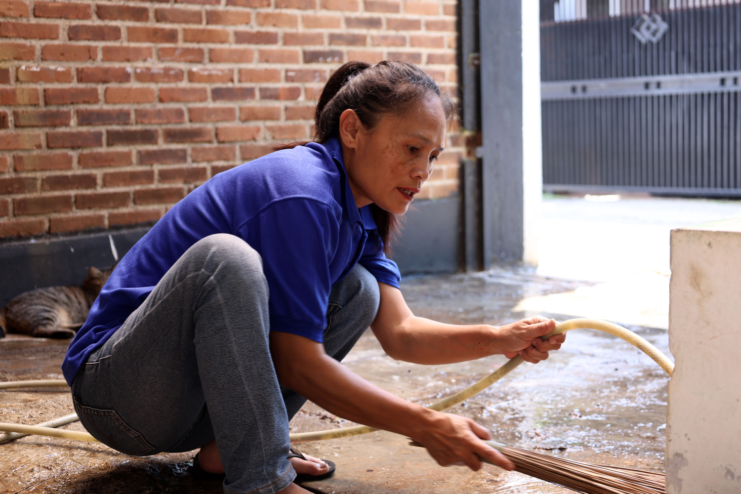 Homeowner cleaning water from floor after appliance leak — swift cleanup needed to prevent damage