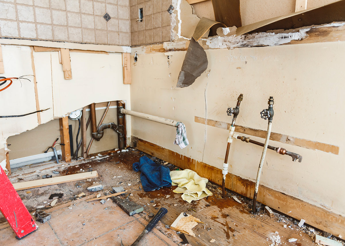 Severe water damage with exposed structure and pipes — emergency water damage restoration in progress